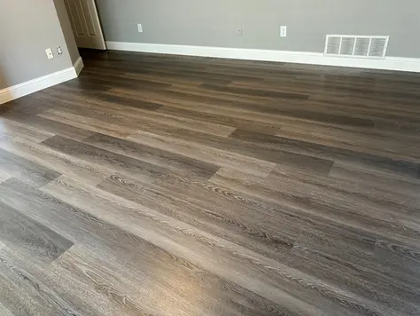 Luxury vinyl plank flooring installed in a Prosper TX bedroom with dark wood-look planks and modern gray walls