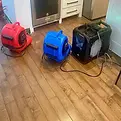 Drying process underway in Allen TX kitchen with air movers and dehumidifier on hardwood floors