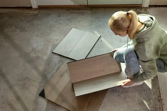Homeowner comparing laminate flooring samples with realistic wood textures before installation — durable and affordable flooring option by Floors To Ceiling Restoration