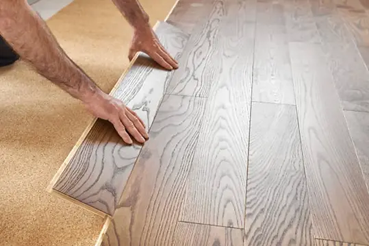 Installer fitting luxury vinyl plank flooring with realistic wood texture — durable, waterproof flooring option installed by Floors To Ceiling Restoration