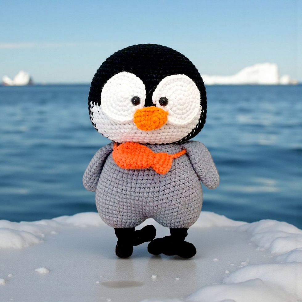 Front view of handmade crochet penguin plush with orange beak and matching scarf, soft grey and black yarn body.