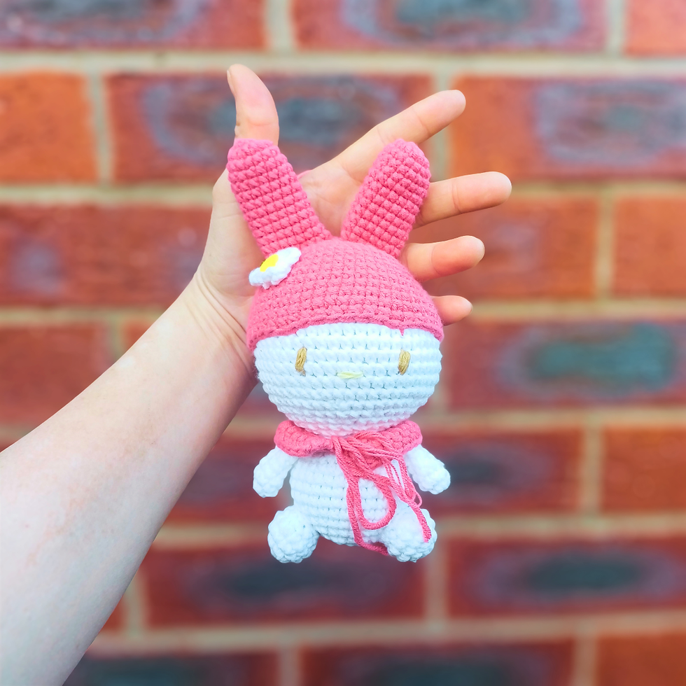 Thumbnail: Close-up of a handmade pink bunny amigurumi keychain with long ears and flower detail.