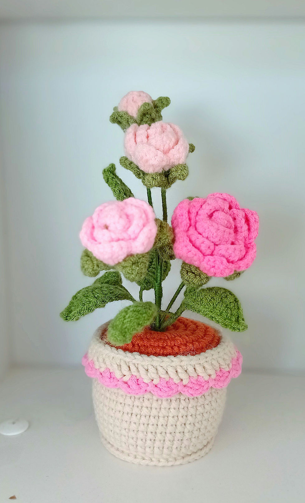 crochet pink rose potted flower in white background.