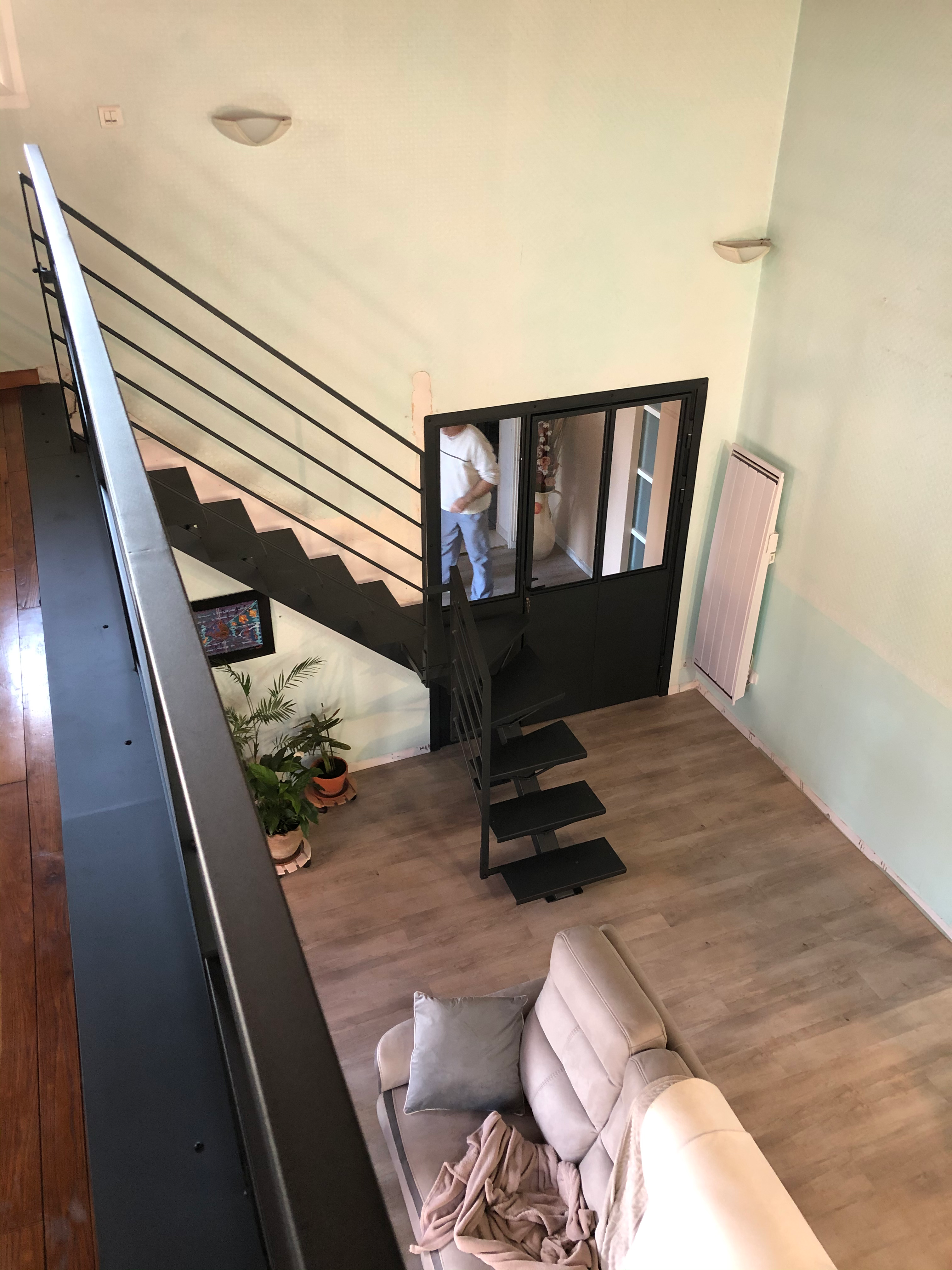 Intérieur, escalier noir, porte vitrée, pièce avec canapé, plantes, escalier & rampe.