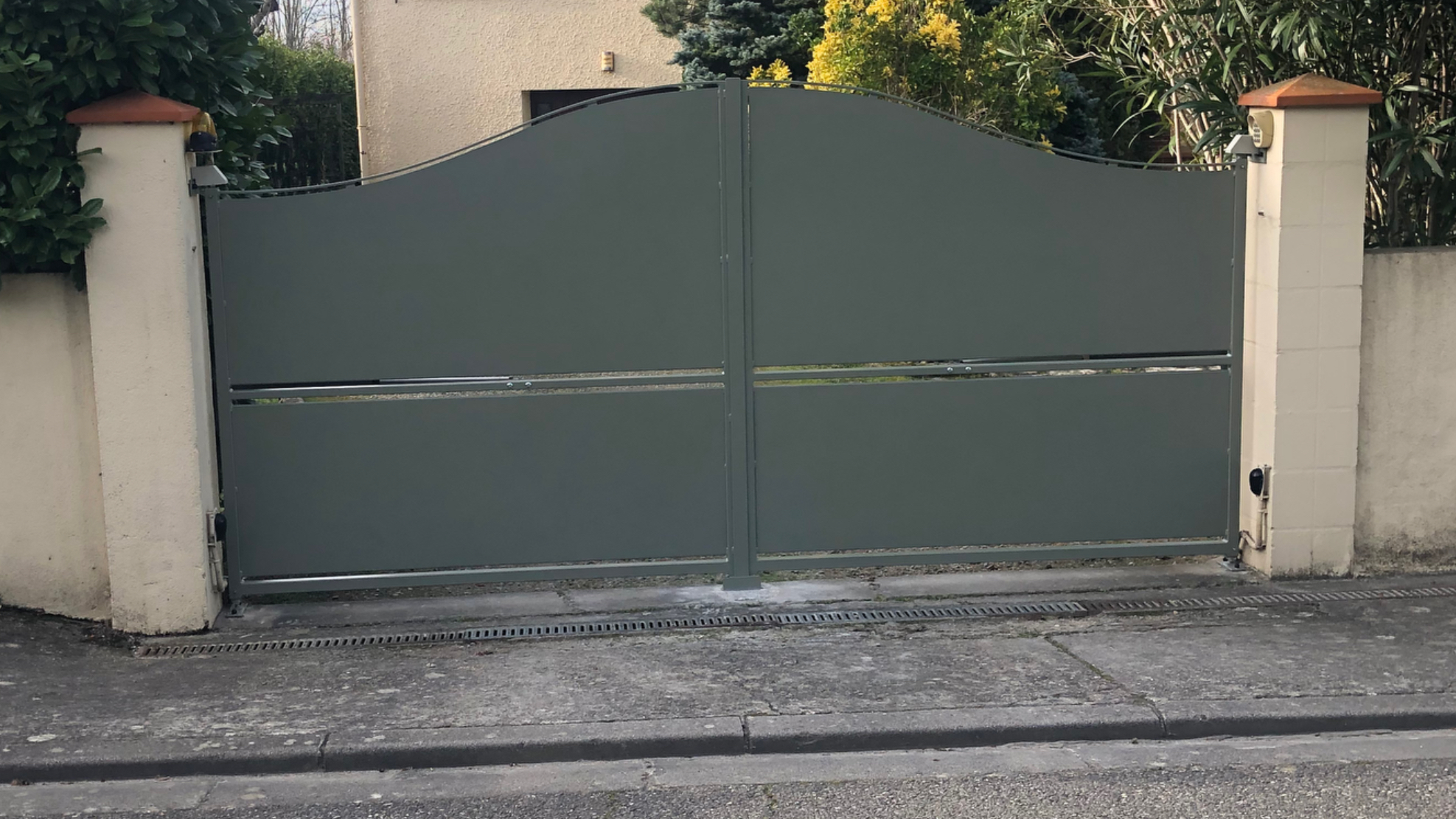 La porte verte fermée. Maison en arrière-plan, vue extérieure, avenue, temps nuageux.