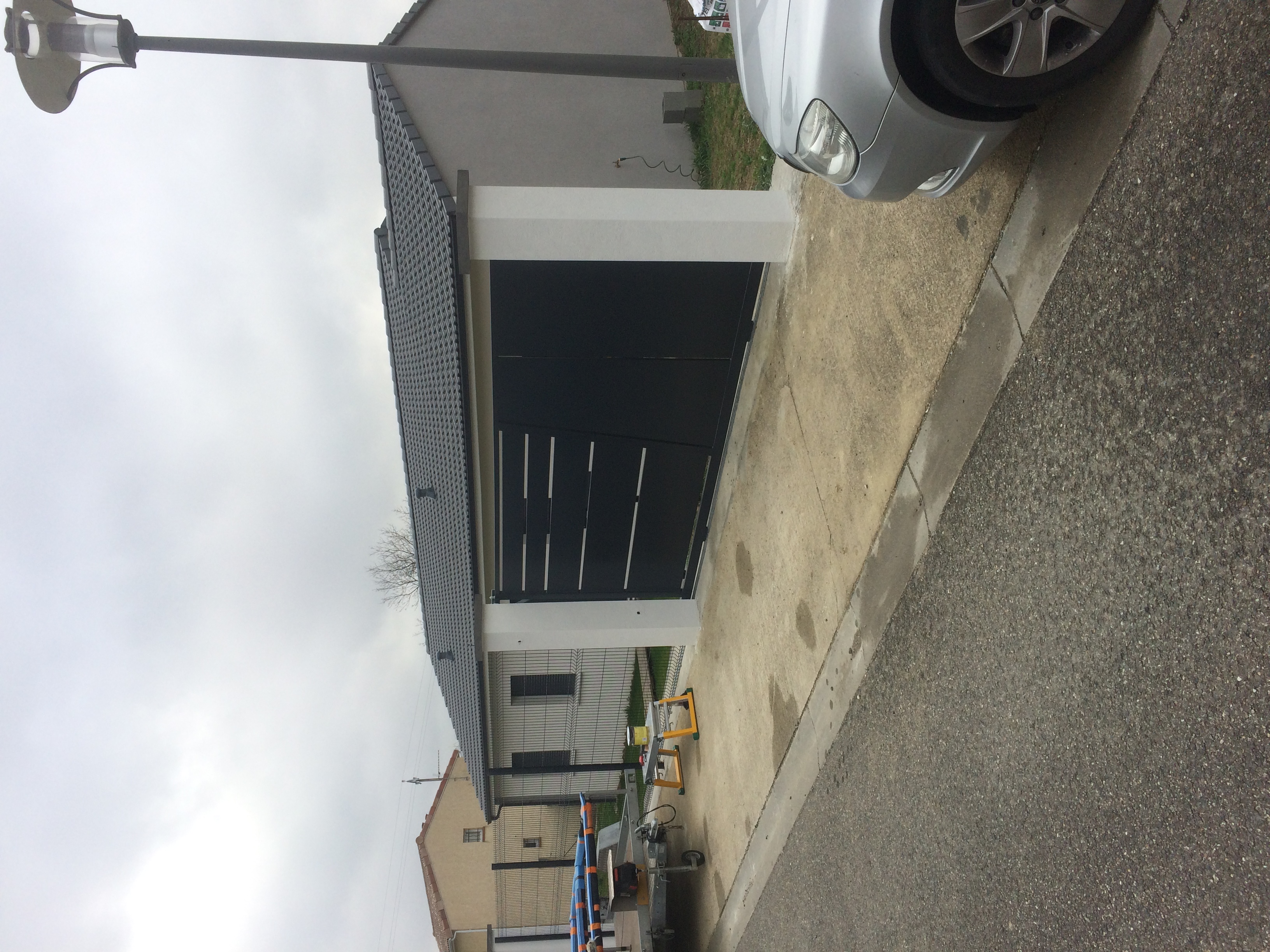 Garage noir fermé. Une maison blanche avec des piliers blancs sur le côté.