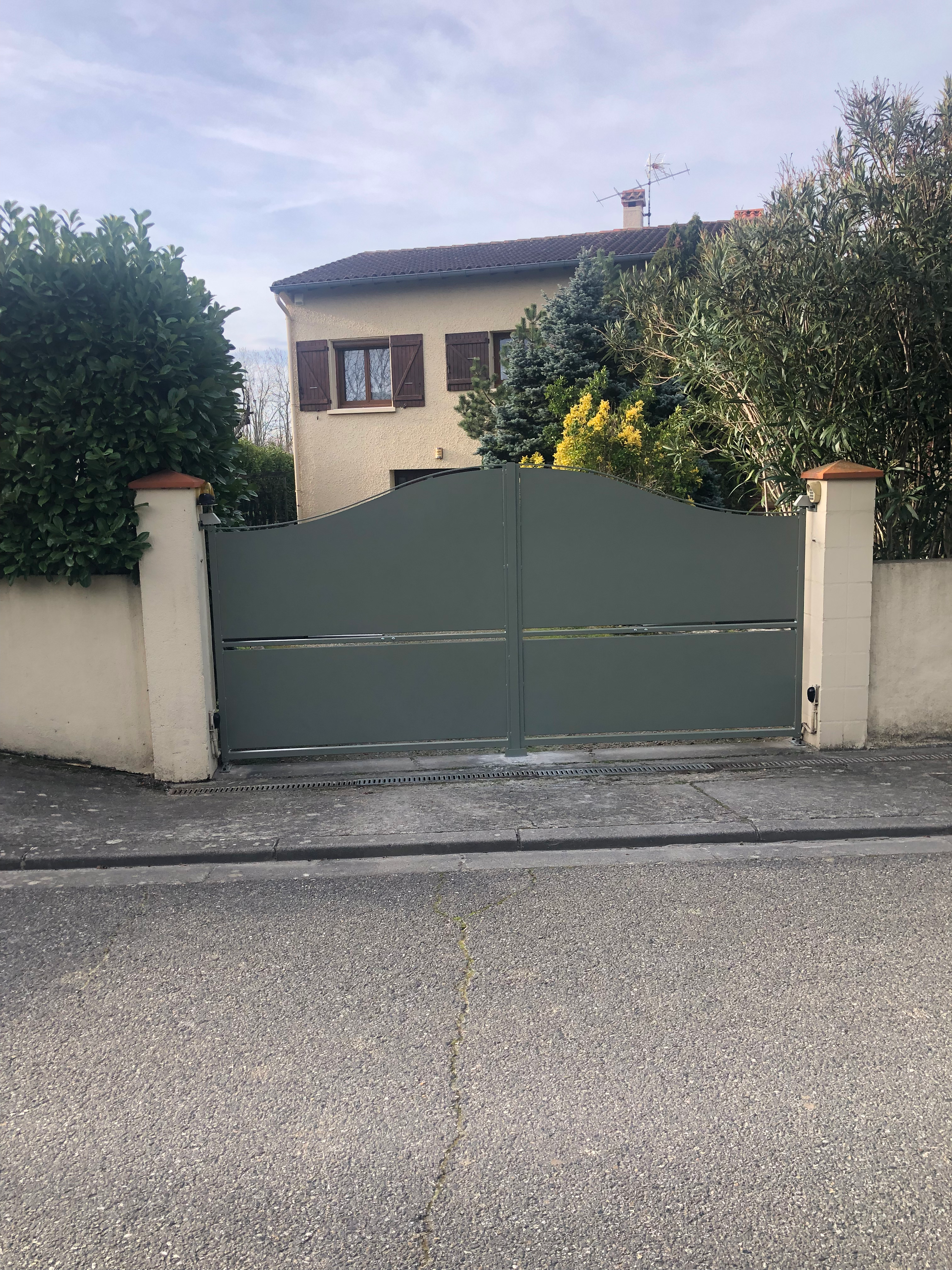 La porte verte fermée. Maison en arrière-plan, vue extérieure, avenue, temps nuageux.