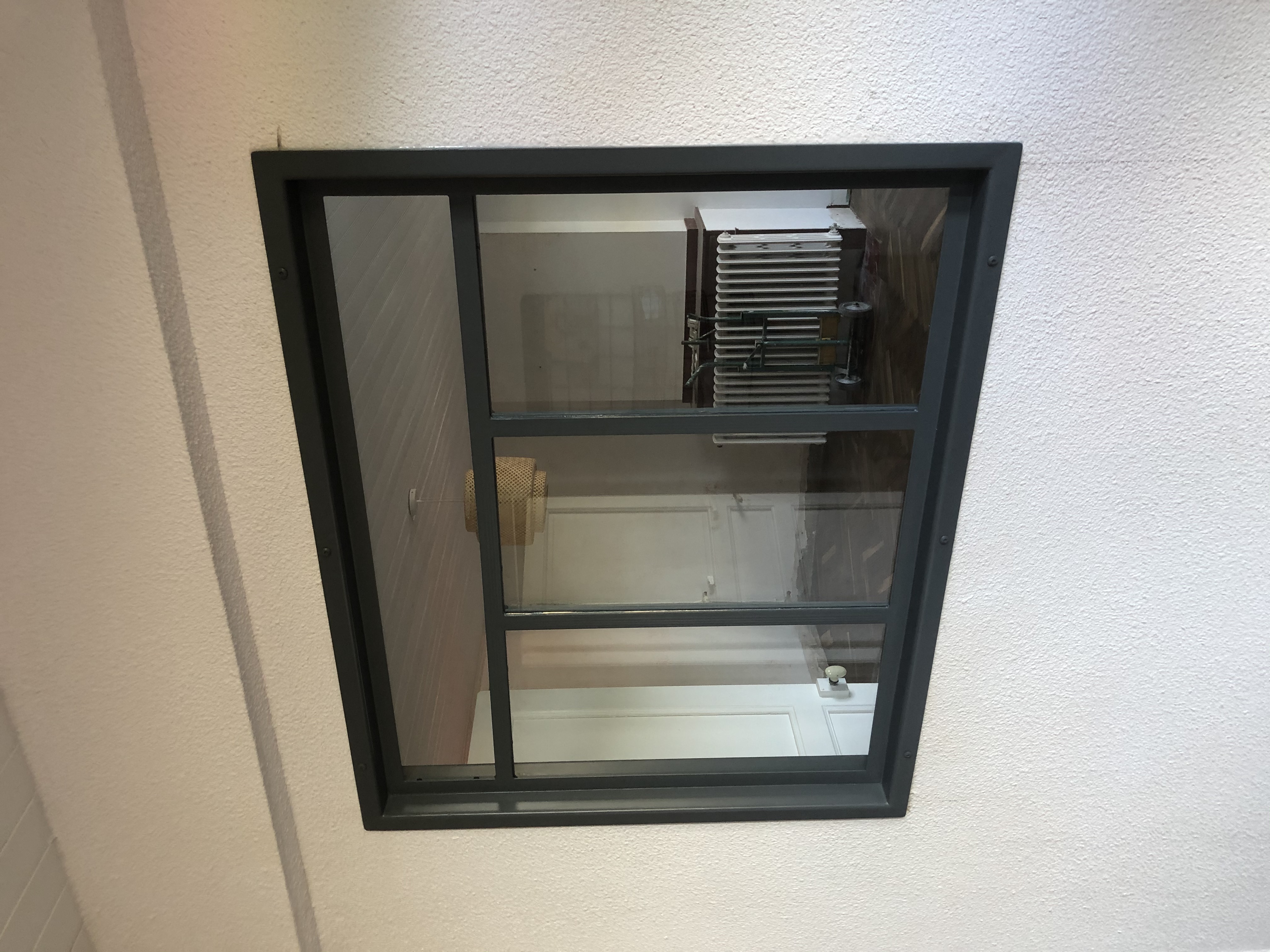 Fenêtre grise encastrée dans un mur blanc, reflet d'une pièce: meubles