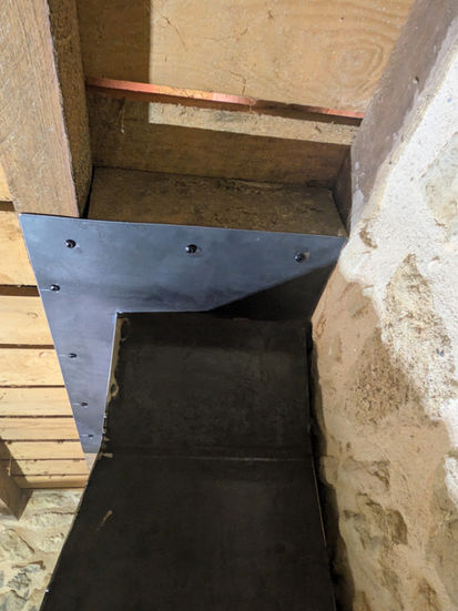 Cheminée en métal noir au-dessus d'un foyer en pierre