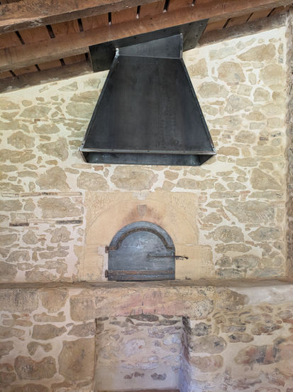 Cheminée en métal noir au-dessus d'un foyer en pierre