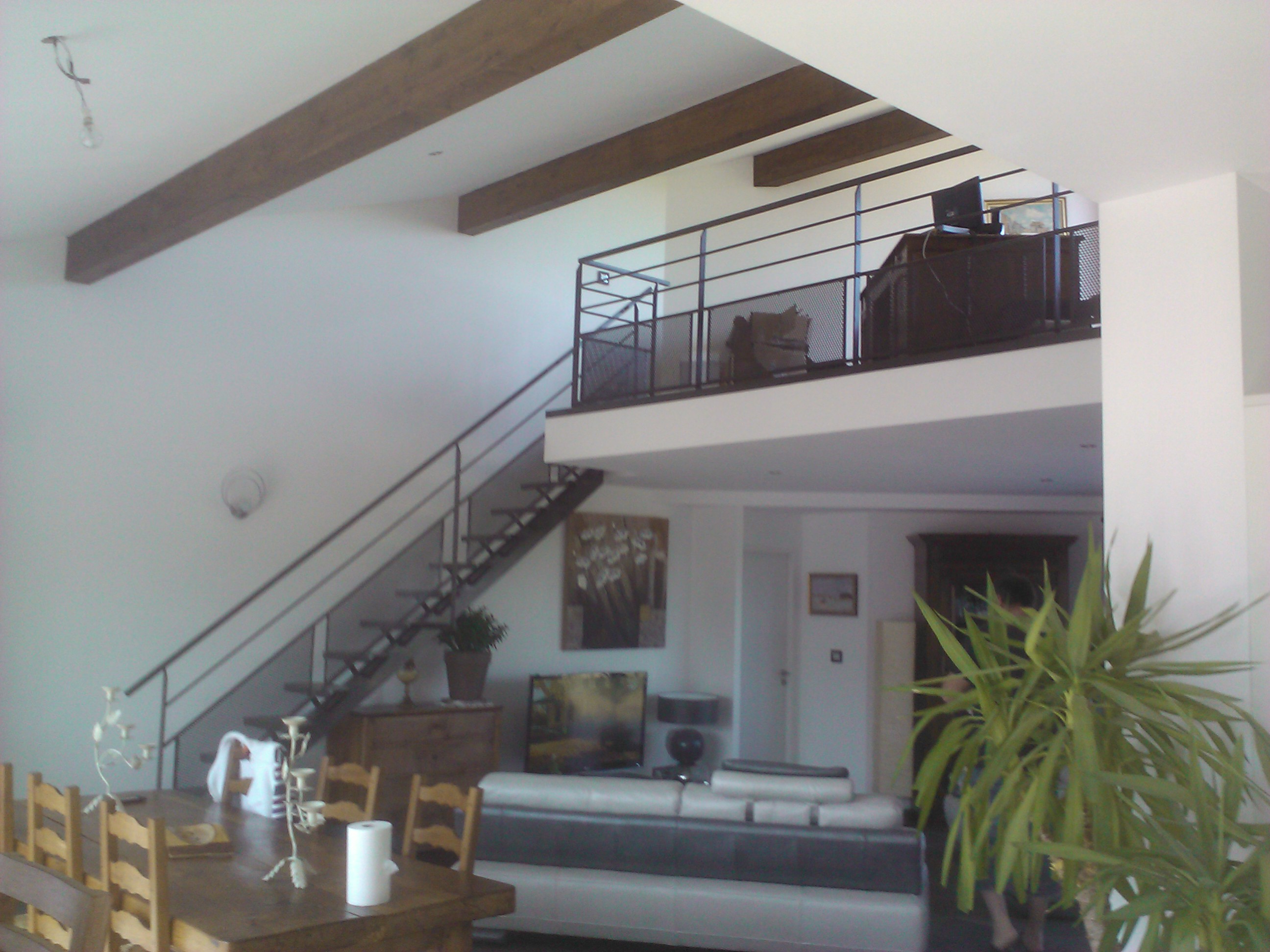 Intérieur avec escalier, rampe, poutres apparentes, salon et meubles; cadre de vie.
