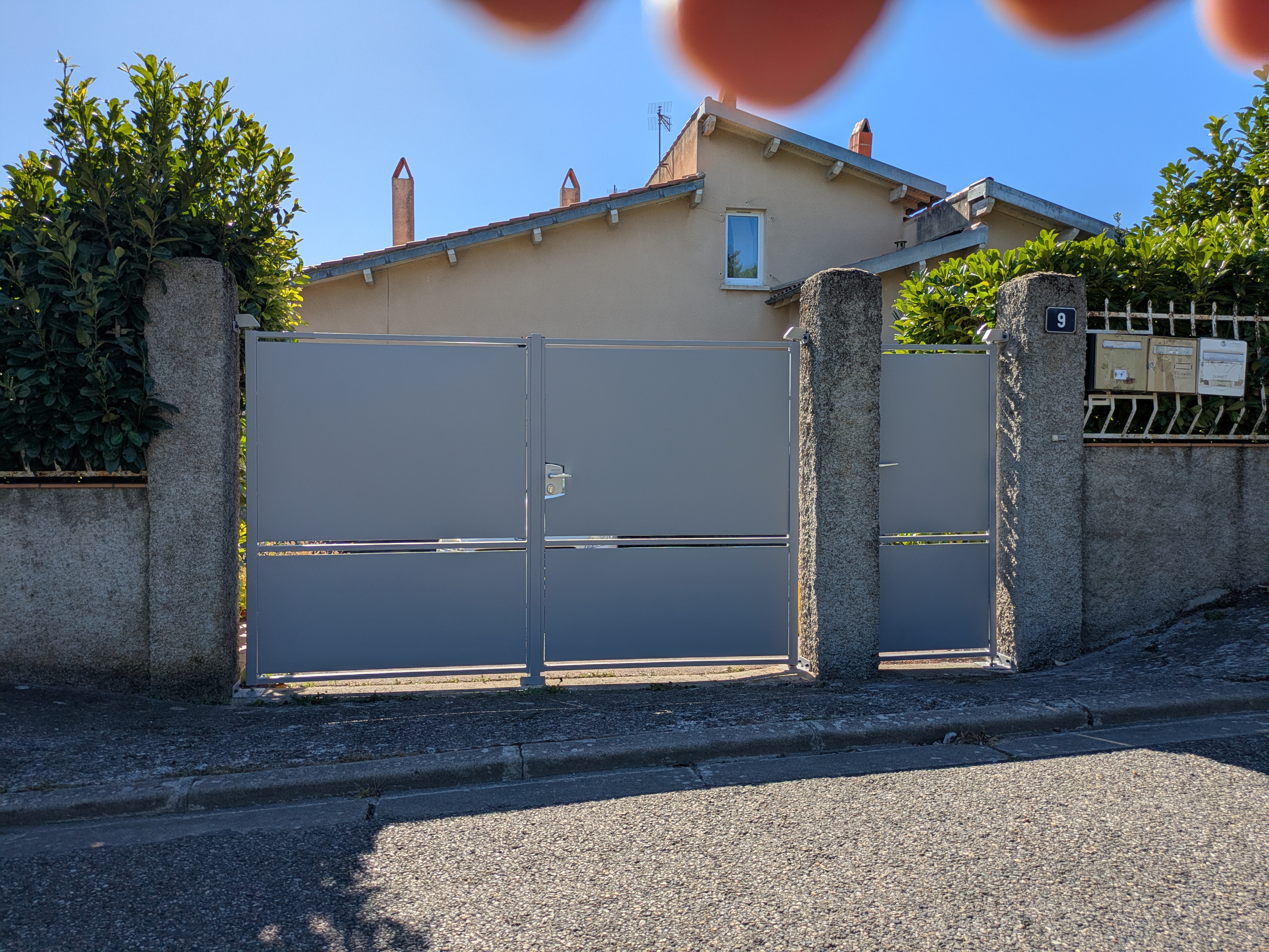 Grand portail gris avec le numéro 1 devant une maison; Portail et rue.