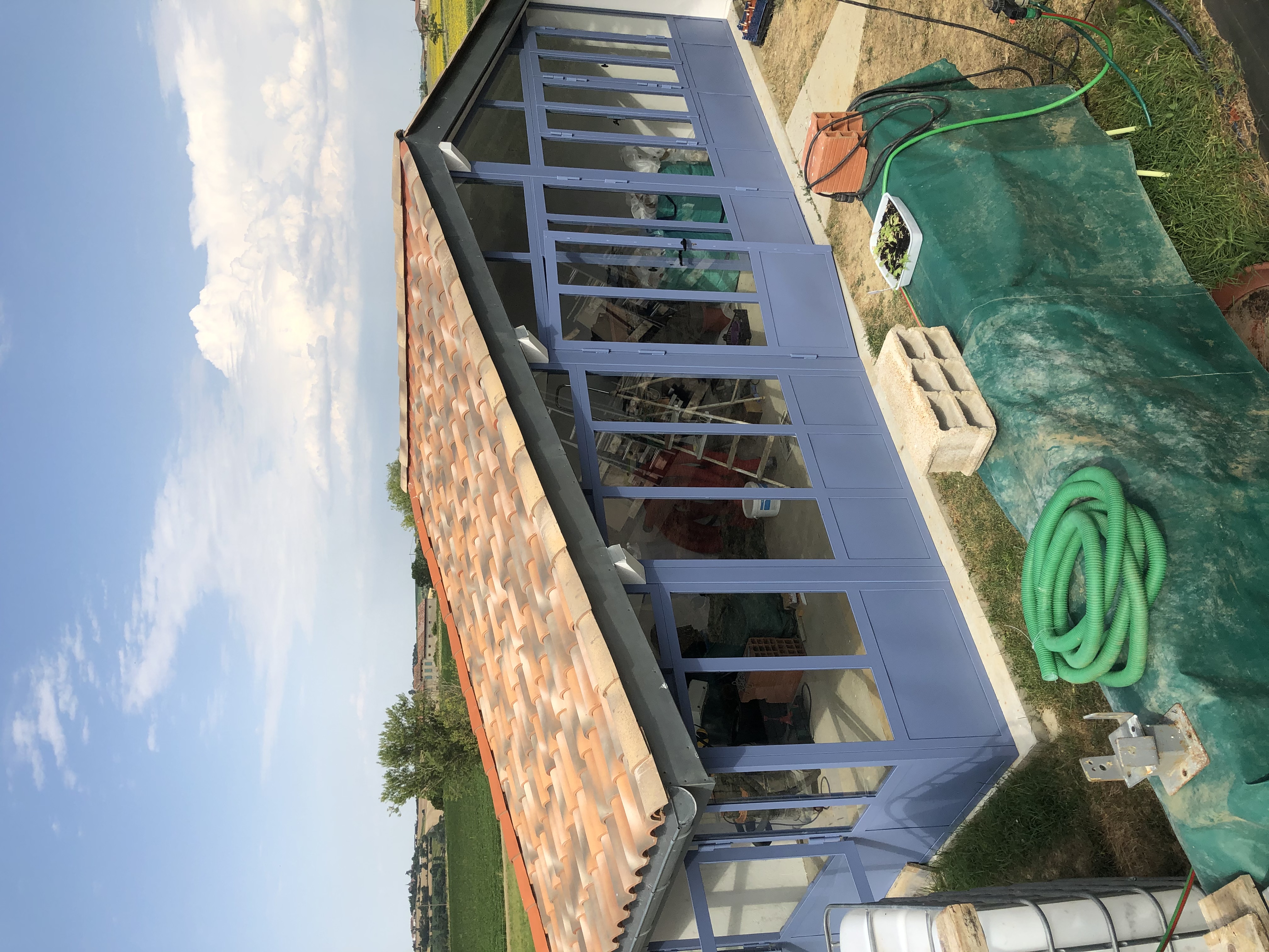 Construction de la Verrière, avec toit en tuiles et fenêtres bleues, par Christo.
