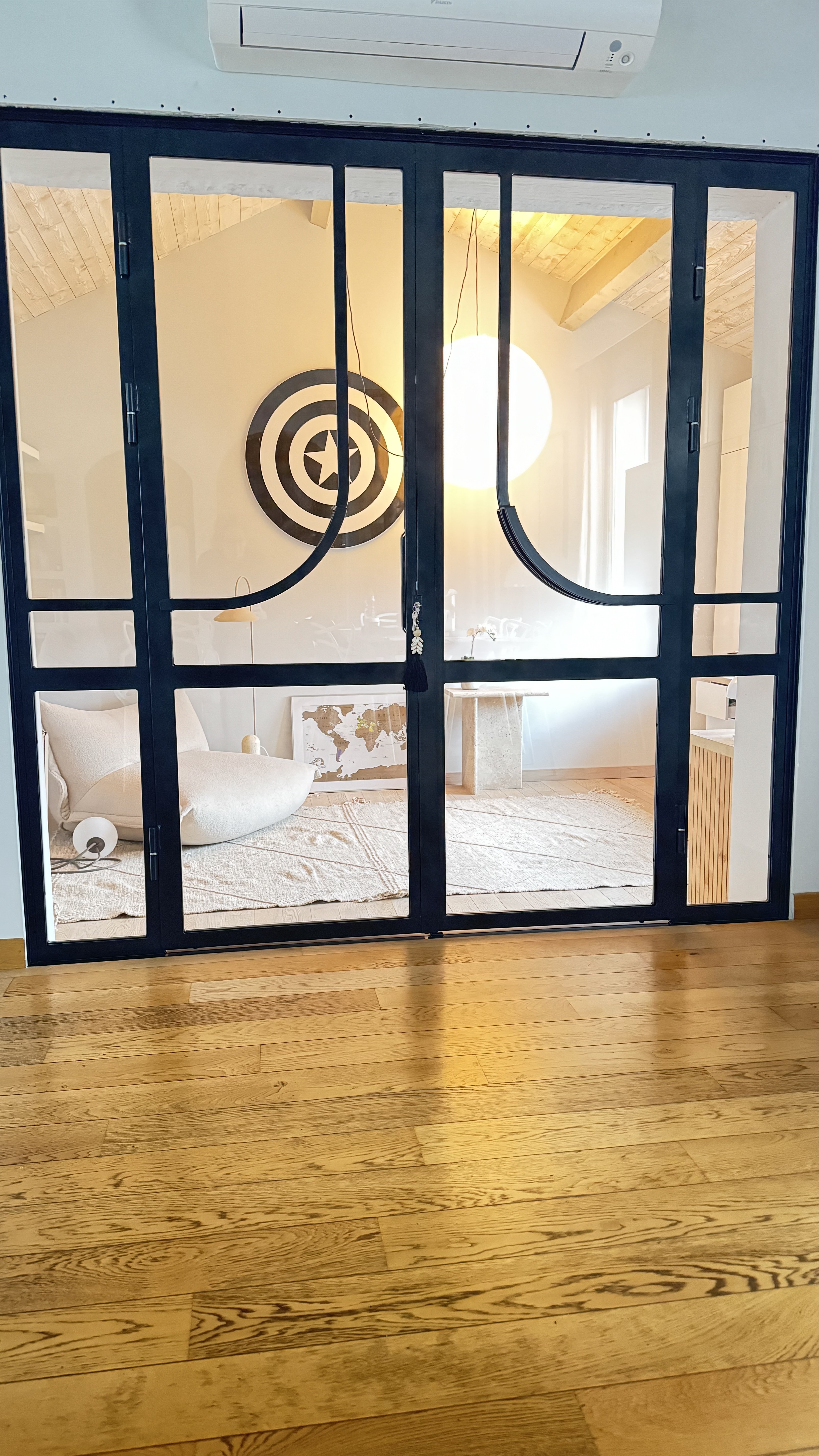 Porte vitrée avec motif circulaire, chambre ensoleillée avec lit et oreillers.