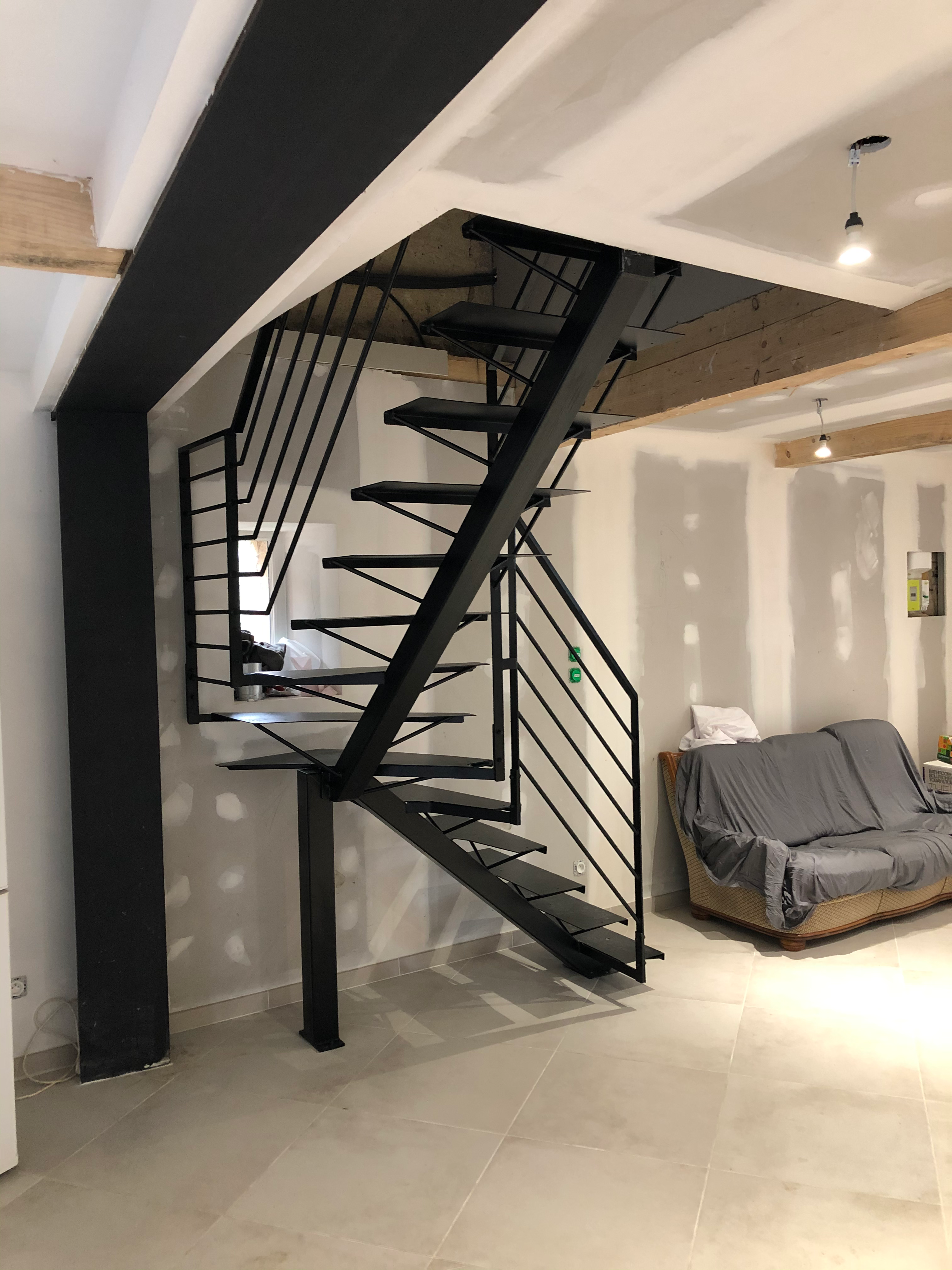 Escalier en métal noir dans un intérieur, avec rampe, en construction, moderne.