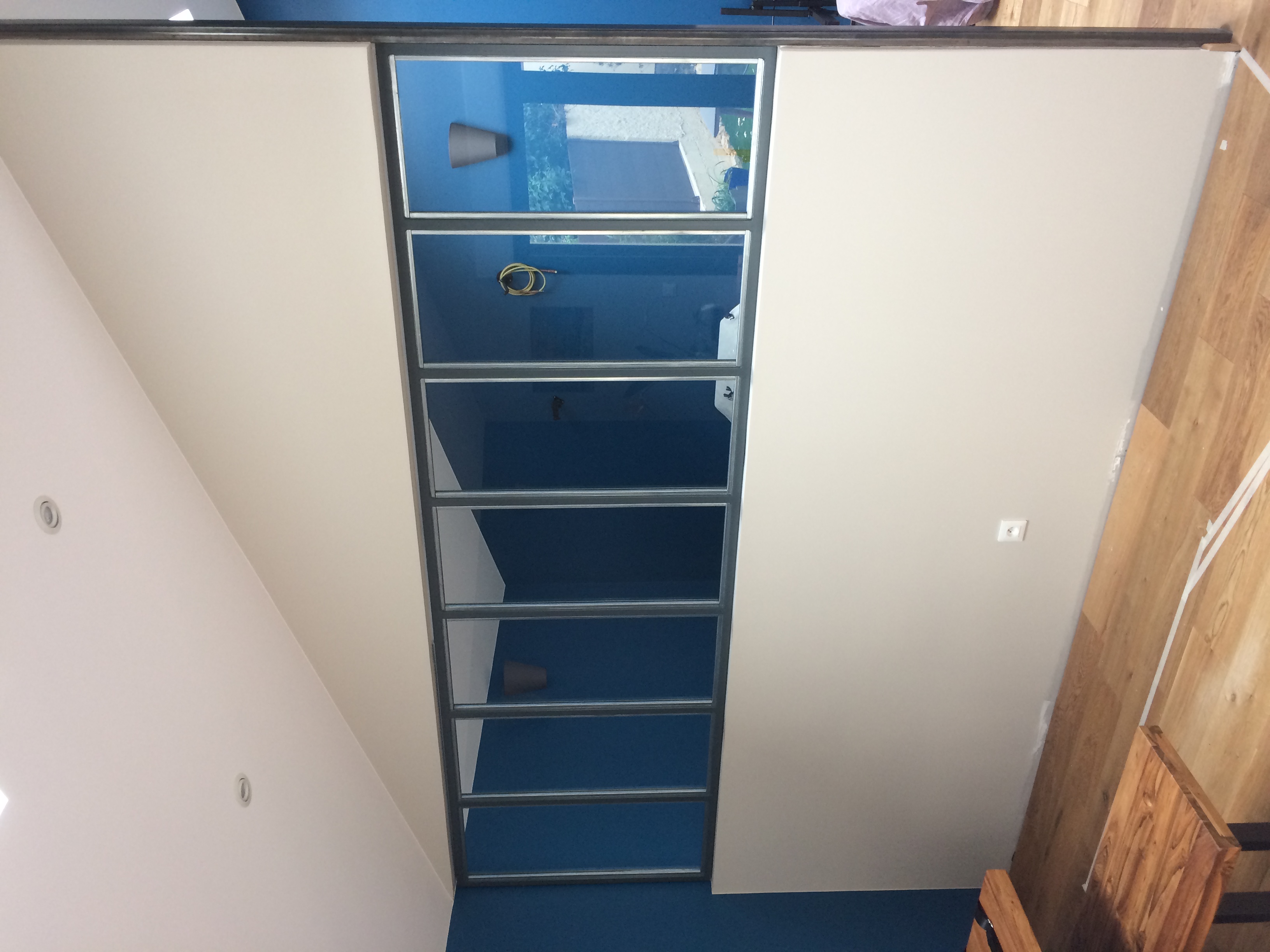 Intérieur avec une verrière, mur bleu et une table en bois. Verrière dans une pièce.