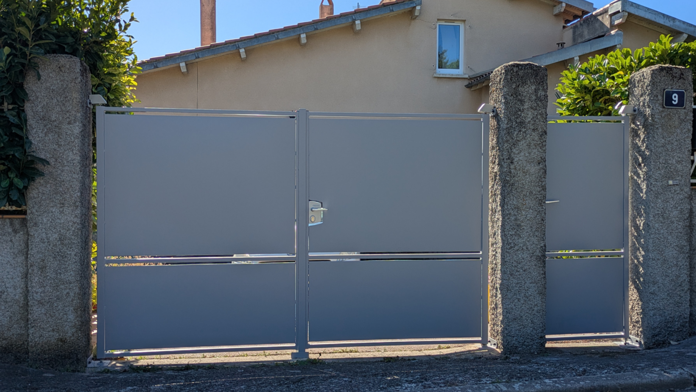 Grand portail gris avec le numéro 1 devant une maison; Portail et rue.