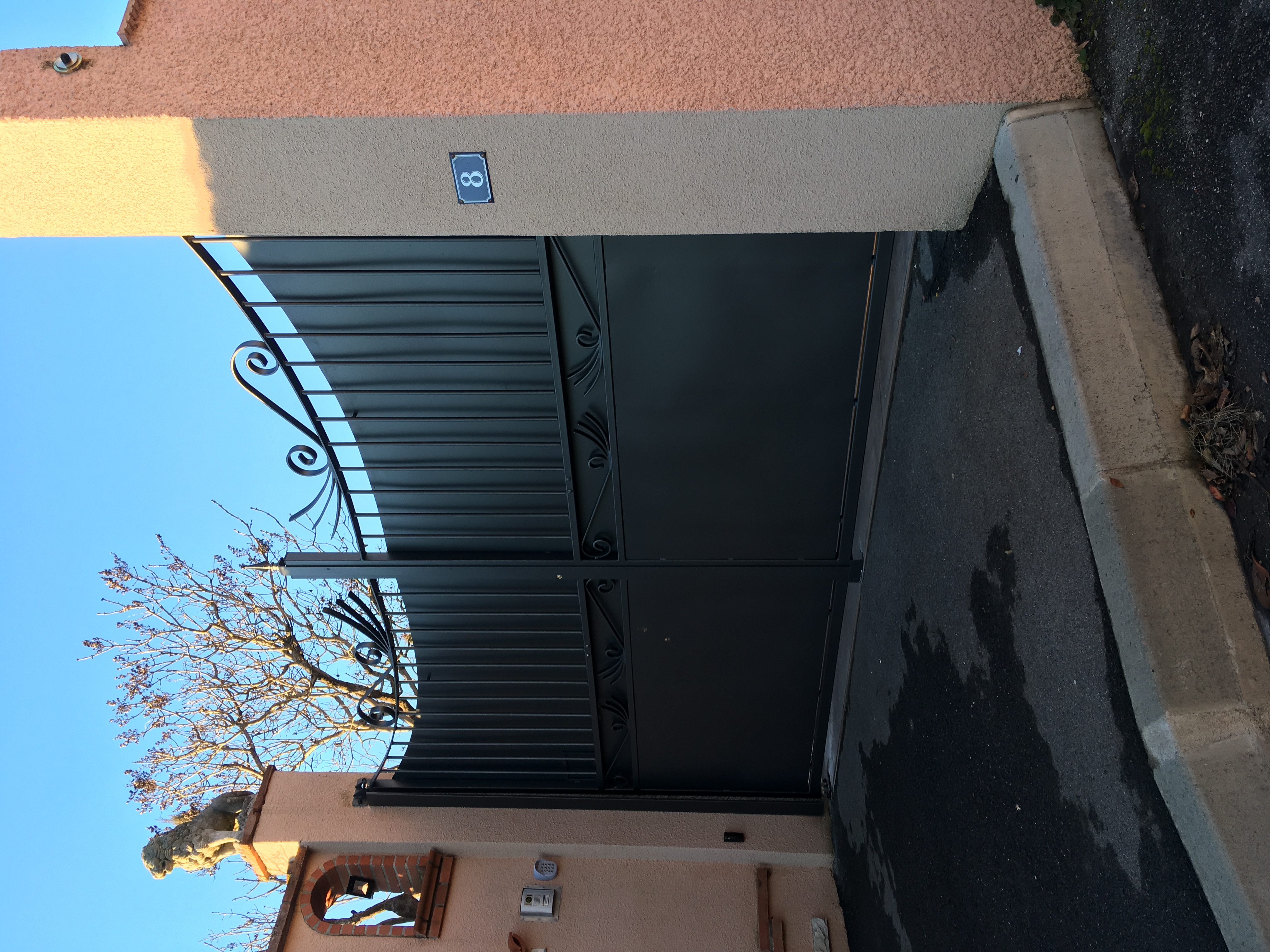 Grand portail en métal fermé; numéro 16 bleu sur le pilier de l'entrée.