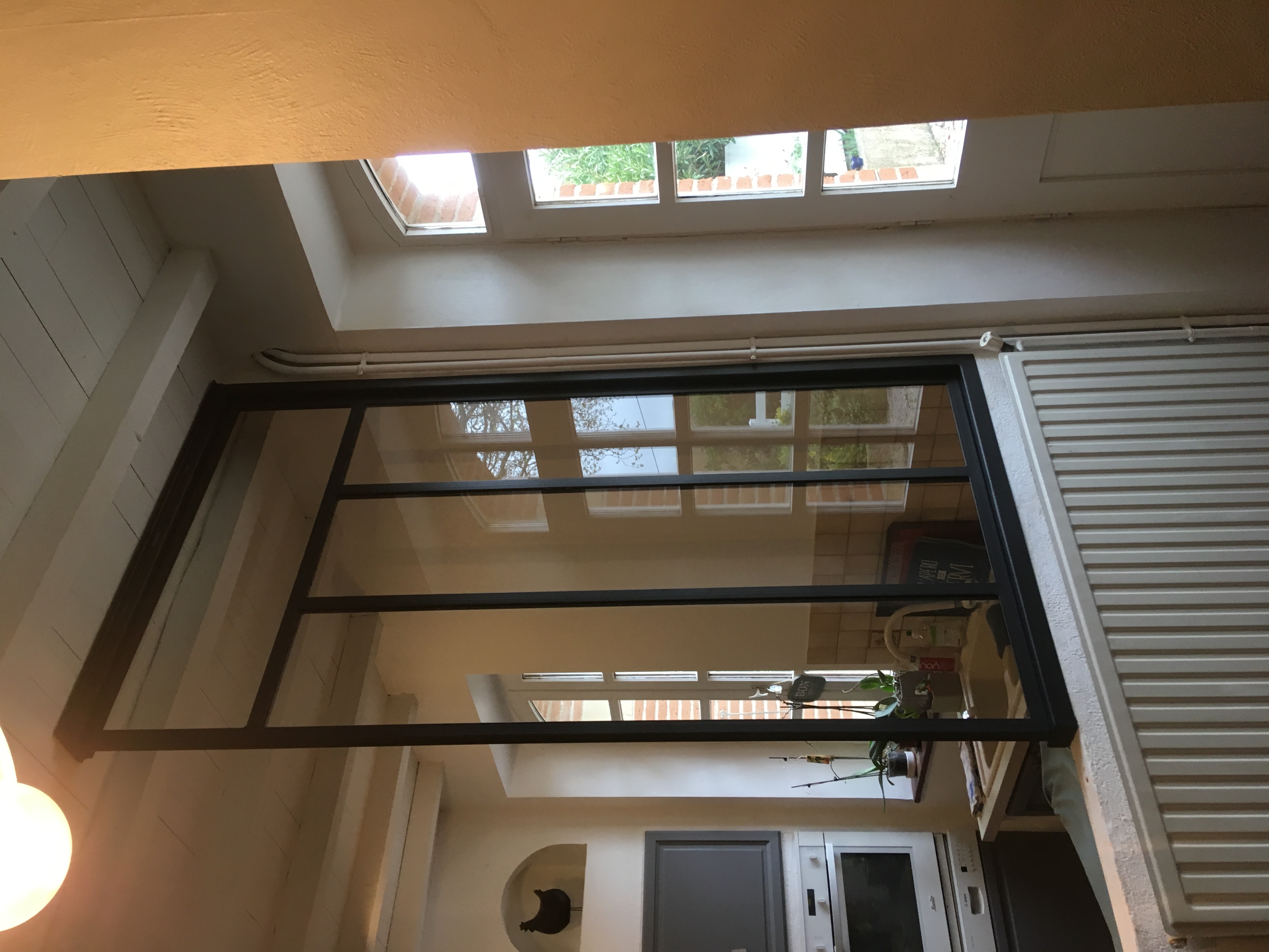 Verrière noire dans une cuisine, séparation avec reflet de la pièce.