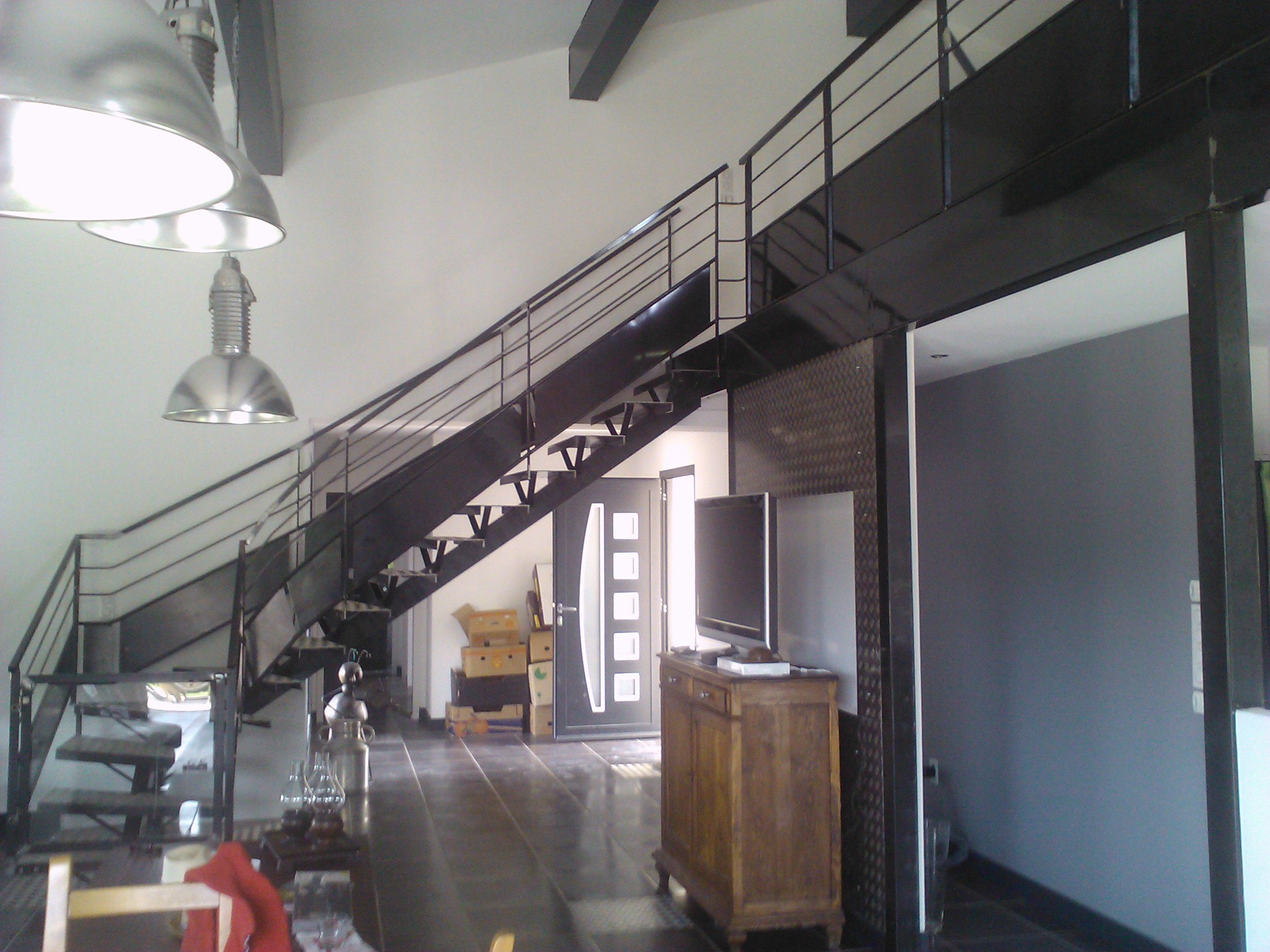 Intérieur avec escalier et rampe, une télévision et des meubles en bois, et lumière