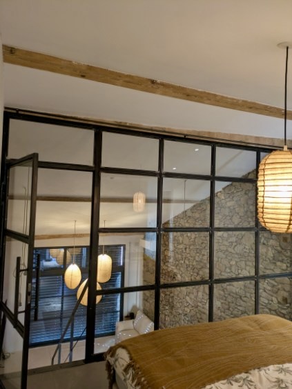 Verrière noire séparant deux pièces, porte verrière coulissante, intérieur moderne et lumineux.