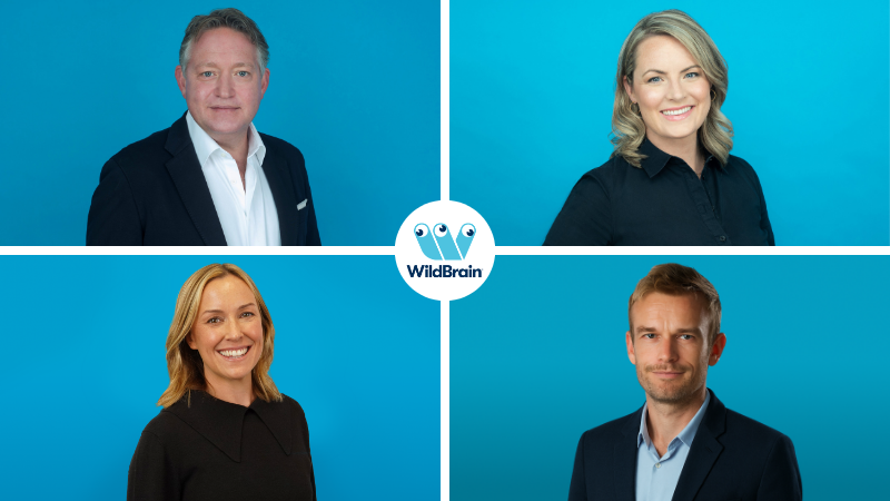 Four professional headshots arranged in a two-by-two grid on a blue background. Each person is shown from the shoulders up. A white WildBrain logo appears at the centre where the four images meet.