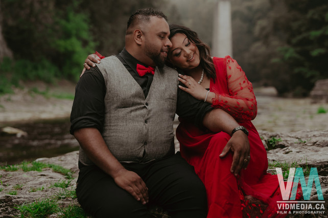 Couple sitting intimately near the Elora Gorge river rocks, taken by an Elora engagement photographer.