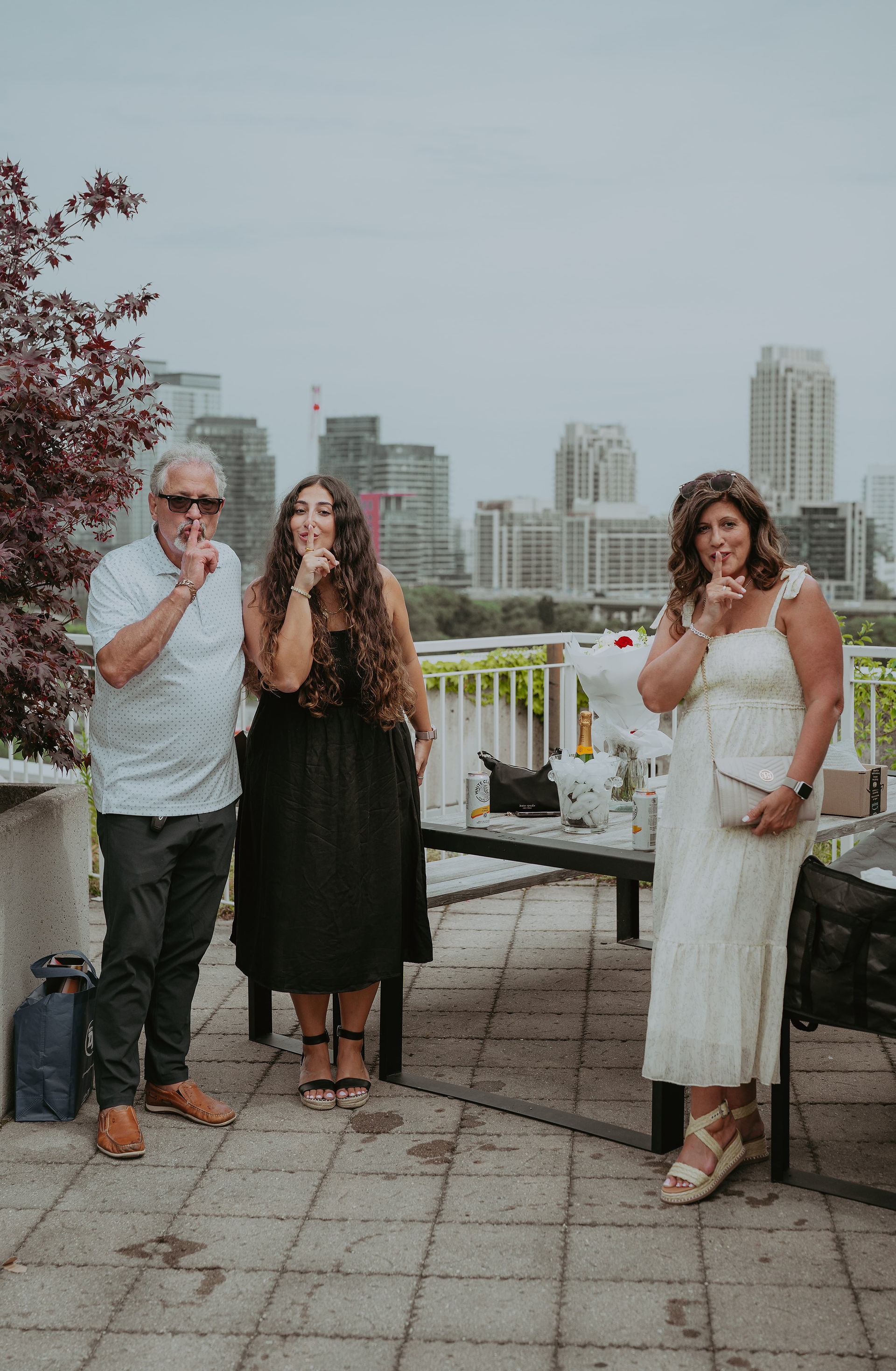 Group photo of a newly engaged couple celebrating with family on a downtown Toronto rooftop patio.