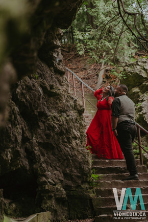 Vertical portrait of an engaged couple surrounded by tall trees in Elora.