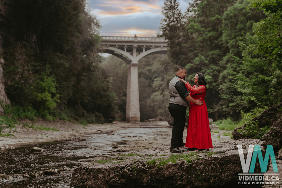 Engaged couple hugging along the Elora riverbed.