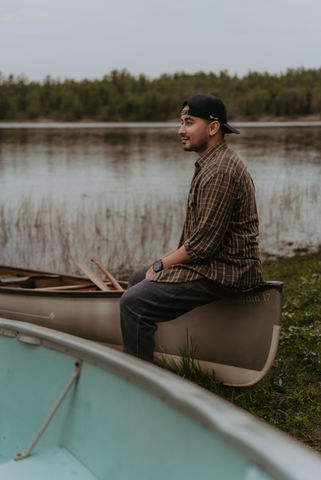 man sitting on a canoe in french river looking into the distance