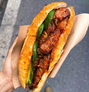 Crispy Hanoi bánh mì sandwich filled with grilled pork, cucumber, and chili sauce.