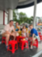 Group enjoying street food on red stools in Hanoi — local-style dining during a food tour