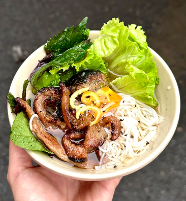 Bún chả in Hanoi with grilled pork, rice noodles, and fresh herbs in a light fish sauce.