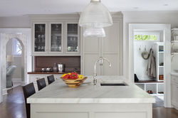 Kitchen looking over white stone island counter towards dining room to the left, white cabinetry wit