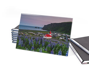 Víkurkirkja, also known as the Church of Vík í Mýrdal, is a striking and iconic church located in the village of Vík í Mýrdal, in southern Iceland. Perched on a hill overlooking the picturesque town, this Lutheran church was completed in 1934 and has since become a symbol of the area. The church is notable for its distinctive architecture, featuring a white exterior with a red roof that stands out against the dramatic backdrop of Iceland's volcanic landscape, including the nearby Reynisfjara black sand beach and the Reynisdrangar sea stacks. The interior of Víkurkirkja is equally charming, with beautiful wooden details and a serene atmosphere. One of the church's most unique features is its stunning stained glass windows, which depict scenes from Icelandic history and folklore. The church also serves as a community gathering place, hosting various events and services throughout the year. Renowned for its stunning landscapes and dramatic coastal features, Vík is particularly famous for its black sand beaches, with Reynisfjara being the most notable. The black beach at Reynisfjara is characterized by its striking black basalt sand, formed from volcanic activity, and is surrounded by impressive sea stacks known as Reynisdrangar. These towering columns of basalt rise majestically from the sea, creating a breathtaking sight against the backdrop of the Atlantic Ocean. The beach is also known for its powerful waves and strong currents, making it a beautiful yet dangerous spot for visitors. Vík is a gateway to various surrounding region, including the nearby Mýrdalsjökull glacier, the scenic Dyrhólaey promontory, and the striking black cliffs of the coastline. Vík and Reynisfjara are often captivated by the dramatic contrasts of the black sand against the white waves, the green hills, and the occasional sighting of puffins nesting in the cliffs during the summer months.