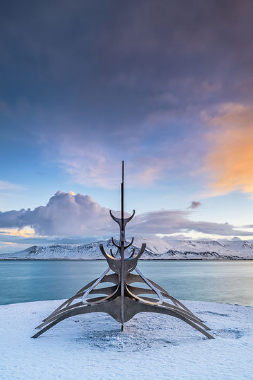 The Sun Voyager, or Sólfar in Icelandic, is an iconic sculpture located in Reykjavik, the capital of Iceland. Created by the Icelandic artist Jón Gunnar Árnason and unveiled in 1990, the sculpture is a striking representation of a Viking ship, symbolizing exploration, hope, and the promise of new horizons.
Crafted from stainless steel, the Sun Voyager features sleek, elongated lines that evoke the image of a ship sailing toward the sun. Its design captures the essence of the Viking spirit, reflecting the adventurous nature of the Icelandic people and their rich maritime history. The sculpture is often interpreted as a dreamboat, representing the dreams of those who seek to discover new lands and experiences.
Situated along the waterfront, the Sun Voyager offers stunning views of both the ocean and the surrounding mountains. It is especially enchanting at sunrise and sunset when the light plays off its metallic surface, creating a mesmerizing effect.
In addition to its artistic significance, the Sun Voyager has become a symbol of Reykjavik and Iceland as a whole. Whether viewed as a tribute to the past or an inspiration for the future, the Sólfar continues to resonate with those who encounter its beauty.