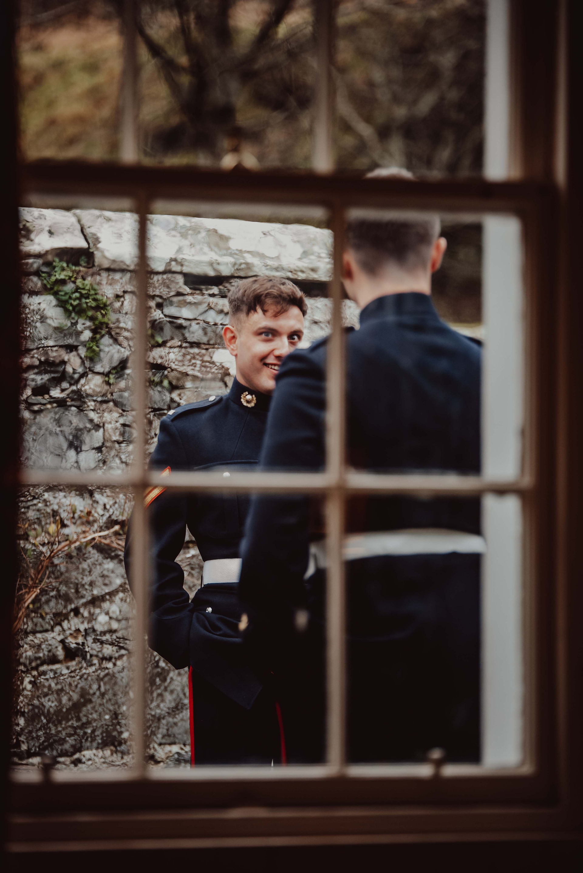 the bestman jokes with the wedding guests through the window at Neidpath