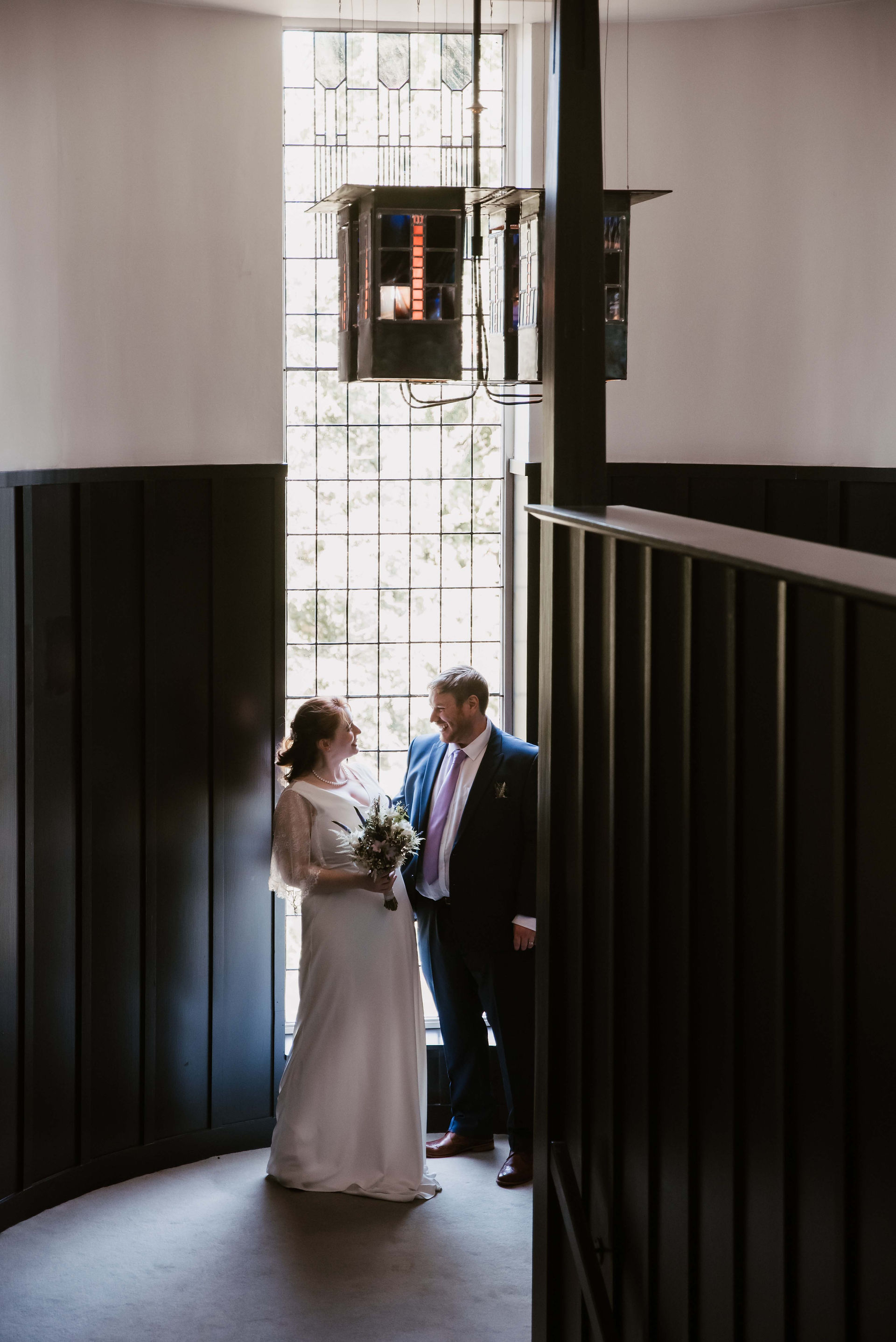 A bride and groom pose in front of a window in House of an Art Lover in Glasgow