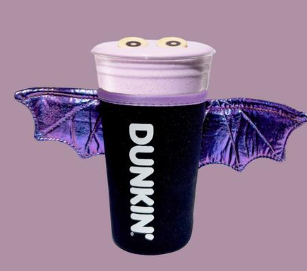 DUNKIN' cup dressed like a purple bat with shiny wings and googly eyes on a mauve background.