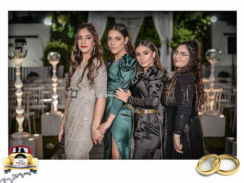 בתמונה נראות ארבע אחיות עומדות צמודות זו לזו ומביטות למצלמה בחיוך. הרקע מואר באורות חתונה, ייתכן גן או אולם אירועים. התמונה משדרת שמחה, קרבה משפחתית ואהבה טבעית בין האחיות ביום מיוחד