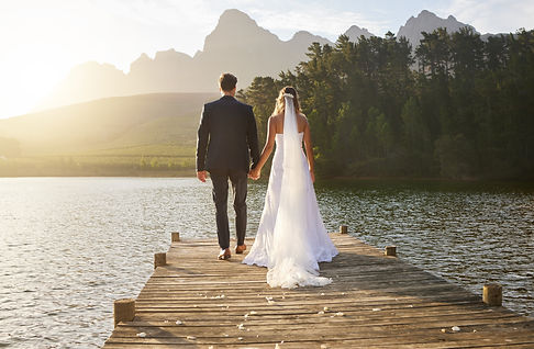 Love, wedding and back of couple by a lake standing, bonding and holding hands on the pier