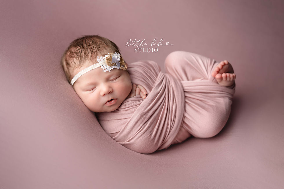 Middletown Ohio Newborn Photography Studio posing baby girl on posing table with dusty pink fabric during her photo session at the studio