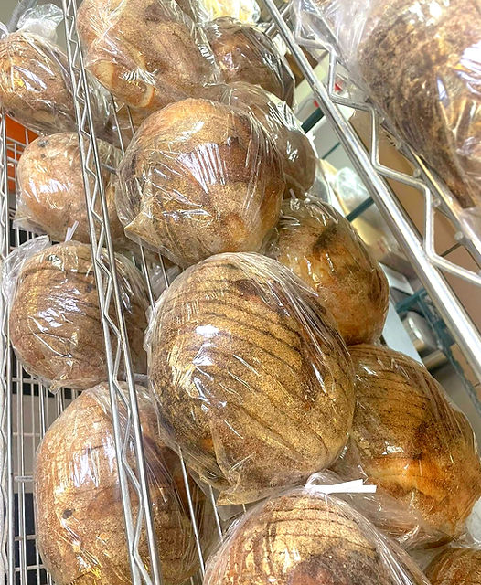 Freshly baked artisan bread loaves wrapped and cooling on racks at Erie Bread Company, a local cottage bakery in Monroe MI