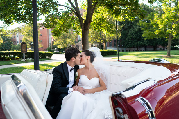 bride and groom kissing in a vintage red car
