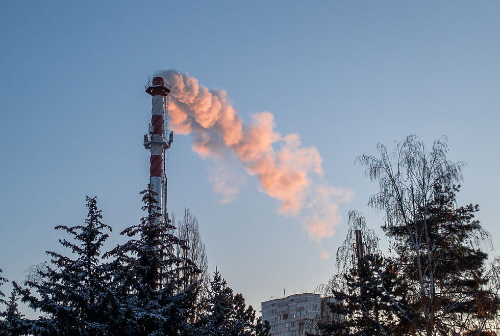 An industrial chimney steaming with a blue sky