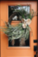 orange door with grapevine wreath and grass greenery