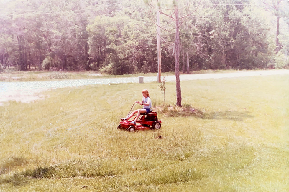 young ginger riding lawn mower in sun