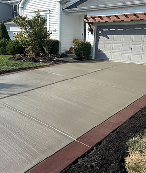 A broom finish driveway with a red border in a suburban neighborhood