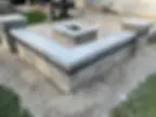 A concrete patio with a firepit and seat walls.